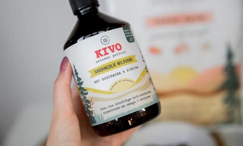 Hand met een fles KIVO Sardineolie wildvang.